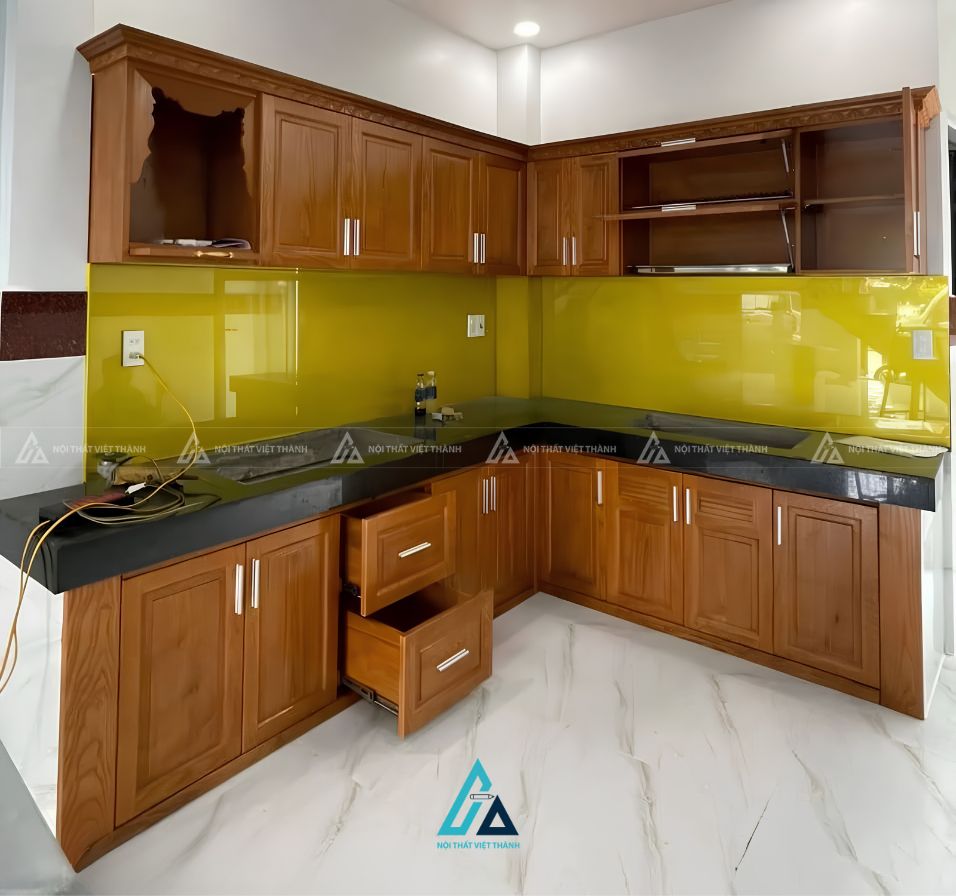 Tủ bếp gỗ tự nhiên chữ L phối kính ốp tường màu vàng nổi bật 1